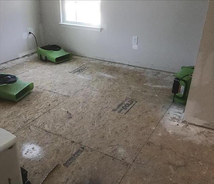flooring removed revealing plywood subfloors with green fans placed for drying
