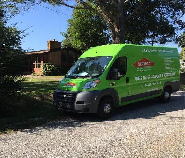residential street with a green SERVPRO van parked on it