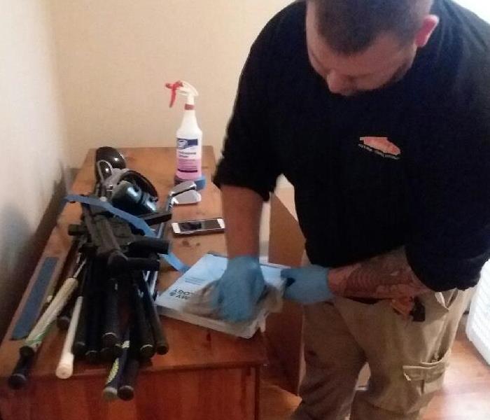 Man wearing blue protection gloves cleaning belongings.