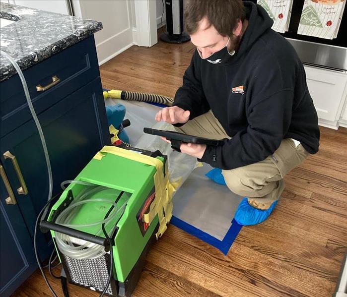 SERVPRO technician beside kitchen cabinet and drying equipment