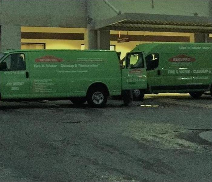 Two green vans getting ready to go on the road