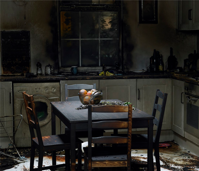 a fire damaged kitchen with soot covering the furniture and counters