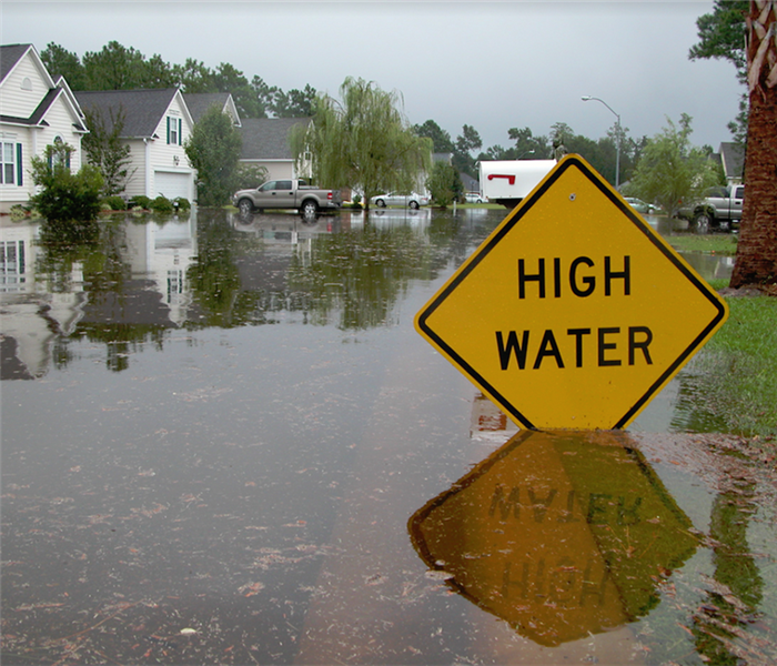 a flooded street with a high water yellow sign